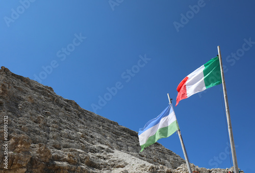 two flag one italian and on e of Ladinia Geographical Area the Alpine region in the Dolomites Zone of Italy and the rocks of Mountain in summer photo