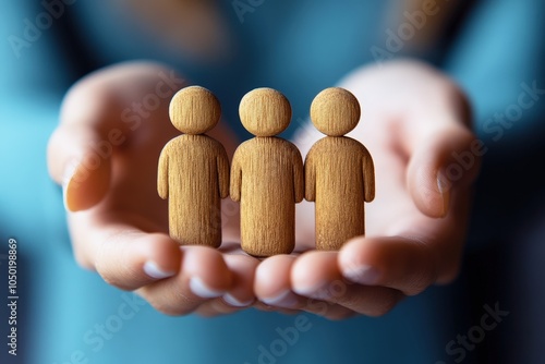 Protecting Our People:  A pair of hands cradle three wooden figurines, symbolizing a commitment to safeguarding and supporting individuals within a community or organization. photo