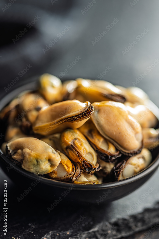 Fototapeta premium Shelled mussels meat in bowl on black table.