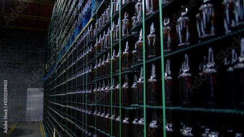Slow motion reveal and move along a huge store of bottles in a factory