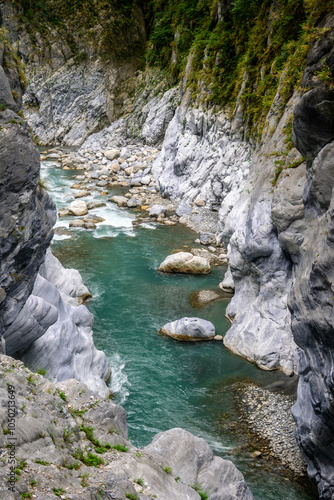 Breathtaking view of a lush green gorge, showcasing a river flowing between dramatic rocky cliffs at the Tunnel of Nine Turns in Taroko National Park in Xiulin, Hualien, Taiwan photo