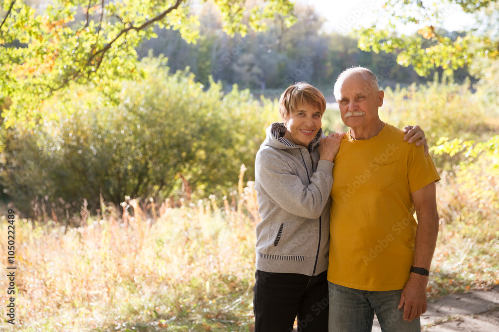 Happy senior couple look at the camera posing and embracing each other on a warm autumn day. copy space. Happy senior couple look at the camera posing and embracing each other on a warm autumn day. copy space.