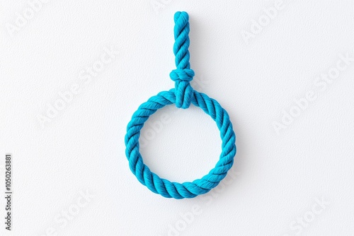 A vibrant turquoise rope knot hangs against a minimalist background, showcasing craftsmanship and color contrast. photo