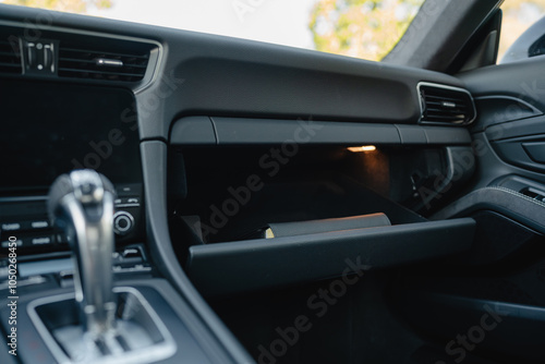 Glove compartment of a luxury car with a sleek handle on a minimalist dashboard.