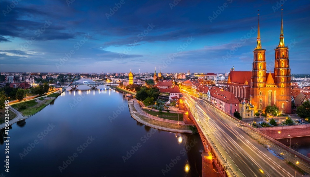 Naklejka premium flyingover oder river to grunwaldzki bridge in wroc aw passing bye rushing traffic on the bridge illuminated historic buildings and bridges beautiful sky light reflections on blurred water