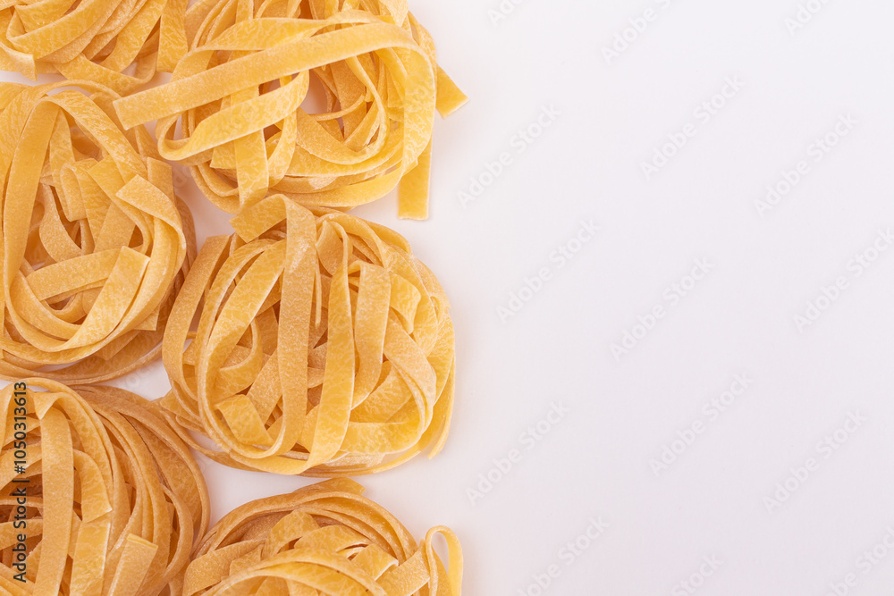 Classic Italian Raw Egg Fettuccine with Copy Spase on White Background. Dry Twisted Uncooked Pasta. Italian Culture and Cuisine. Raw Golden Macaroni Pattern Classic Italian Raw Egg Fettuccine with Copy Spase on White Background. Dry Twisted Uncooked Pasta. Italian Culture and Cuisine. Raw Golden Macaroni Pattern
