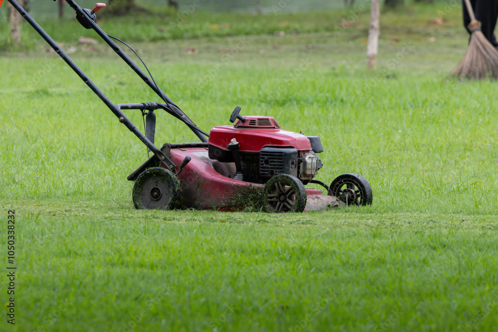 A red lawn mower is on a grassy field A red lawn mower is on a grassy field