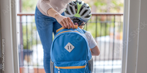 A mother performs a quick check of her child’s school backpack at the door before they head out. The organized moment shows preparation and love in action. photo