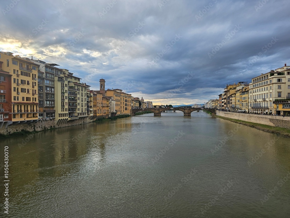 Naklejka premium Florence, Italy - October 5, 2024: Discovering the city of Florence in autumn days. Frome the Duomo to Ponte Vecchio, old architecture covering the city. Beautiful sky reflected over Arno river.