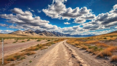 The Dusty Dirt Track Road. Highway in to the mountains, with blue skies and clouds. Ideal Desktop background or Wallpaper.