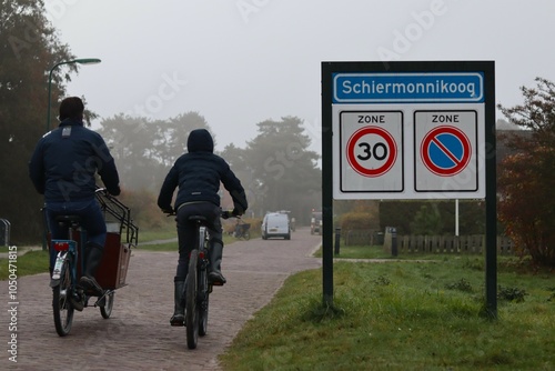 Two people are cycling near a place name sign (Schiermonnikoog in the Netherlands) photo