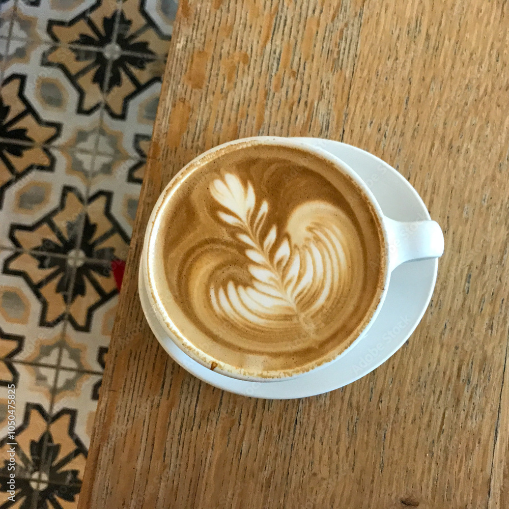cup of coffee on wooden table with tile floor latte art white cup and saucer cup of coffee on wooden table with tile floor latte art white cup and saucer