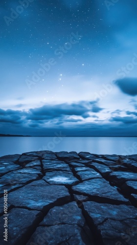 A serene twilight scene featuring cracked rocks leading to calm waters under a starlit sky, evoking tranquility and wonder. photo