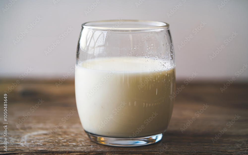 a glass filled with fresh milk. The glass is placed on a wooden surface. a glass filled with fresh milk. The glass is placed on a wooden surface.
