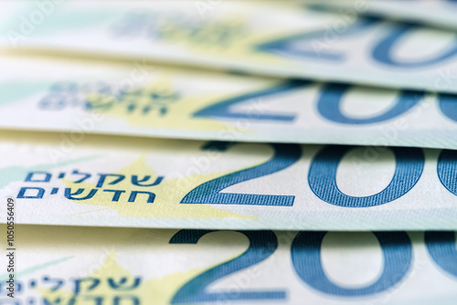 There is a pile of 200 shekel banknotes on the table , a close-up side view , selective focus photo