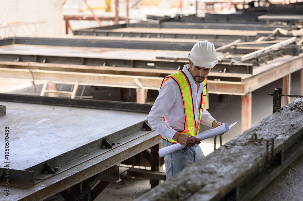 Young engineer wearing a hard hat in a factory inspecting the work on a construction site and pouring cement.