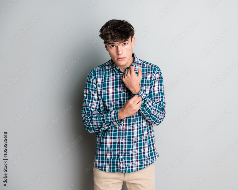 sexy young casual guy adjusting plaid shirt sleeves and posing sexy young casual guy adjusting plaid shirt sleeves and posing