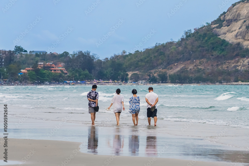 Back view of happy carefree family walk in sea at beach. Summer, travel and relax with family on beach for vacation, bonding and love. Freedom,Group of people walk together at seaside.Holiday outdoors