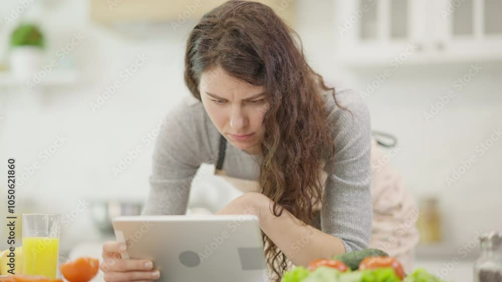A woman learns exciting recipes on her tablet in a stylish kitchen, surrounded by fresh, vibrant ingredients A woman learns exciting recipes on her tablet in a stylish kitchen, surrounded by fresh, vibrant ingredients