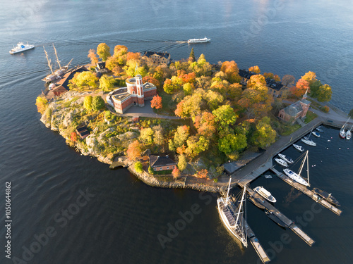 Kastellholmen red castle on island with Stockholm skyline in the background on a sunny autumn morning with turning yellow and orange trees in Sweden photo