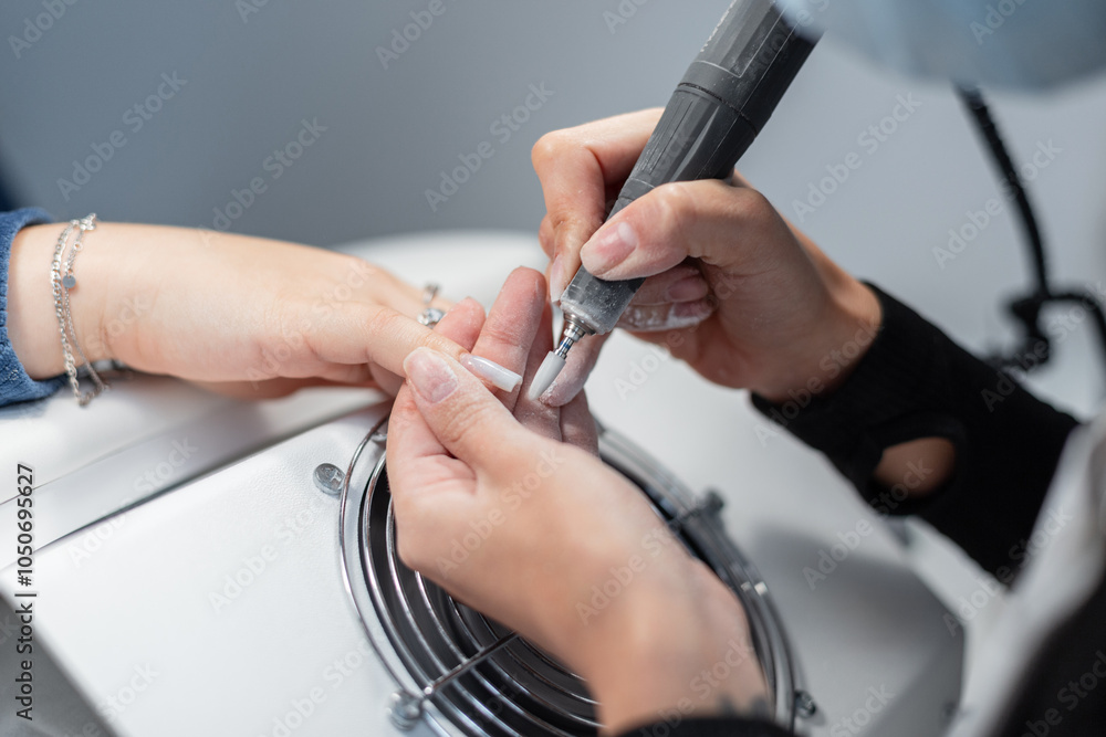 Professional manicurist girl doing manicure and polishing nail with drill machine in beauty studio. Hand care Professional manicurist girl doing manicure and polishing nail with drill machine in beauty studio. Hand care