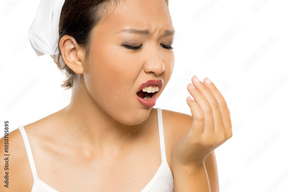 Portrait of young Asian woman checking her breath on white background. Portrait of young Asian woman checking her breath on white background.