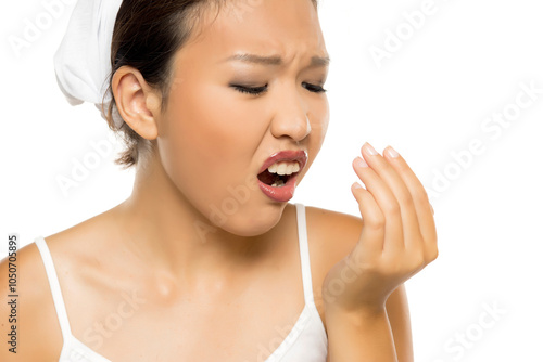 Portrait of young Asian woman checking her breath on white background.