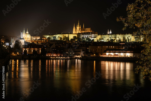 city center of Prag at night, photographed by vltava river with the fortress and Charles Bridge in the background