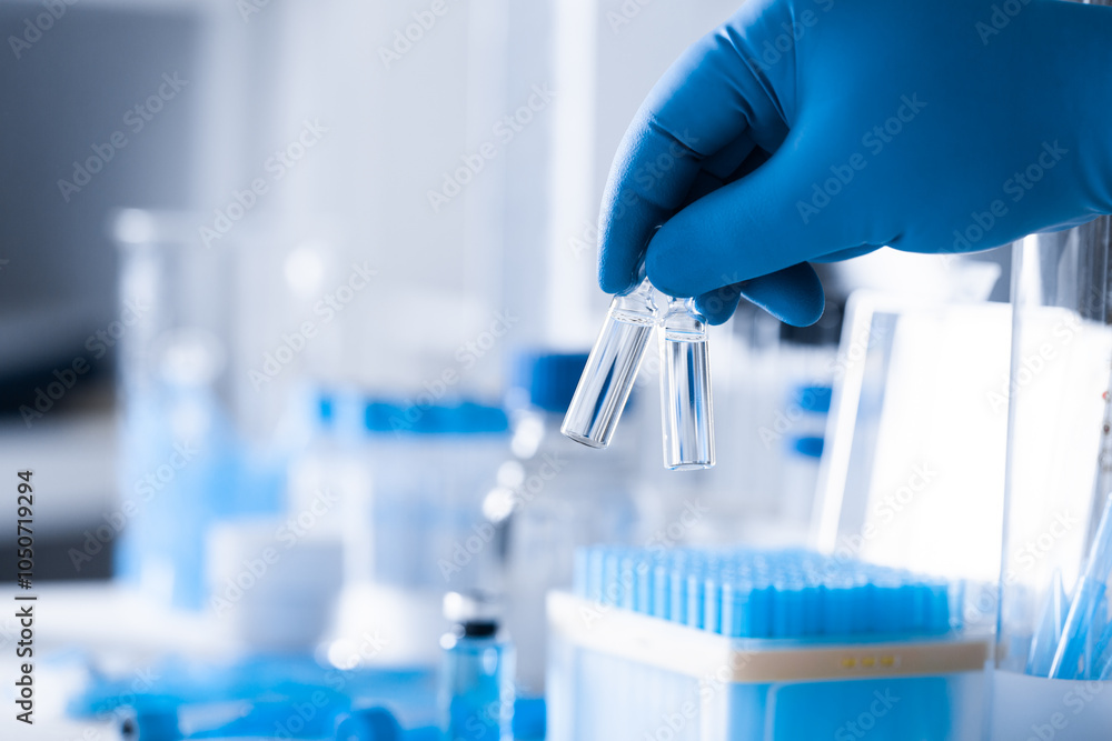 A scientist's hand in a medical glove holds a test tube A scientist's hand in a medical glove holds a test tube