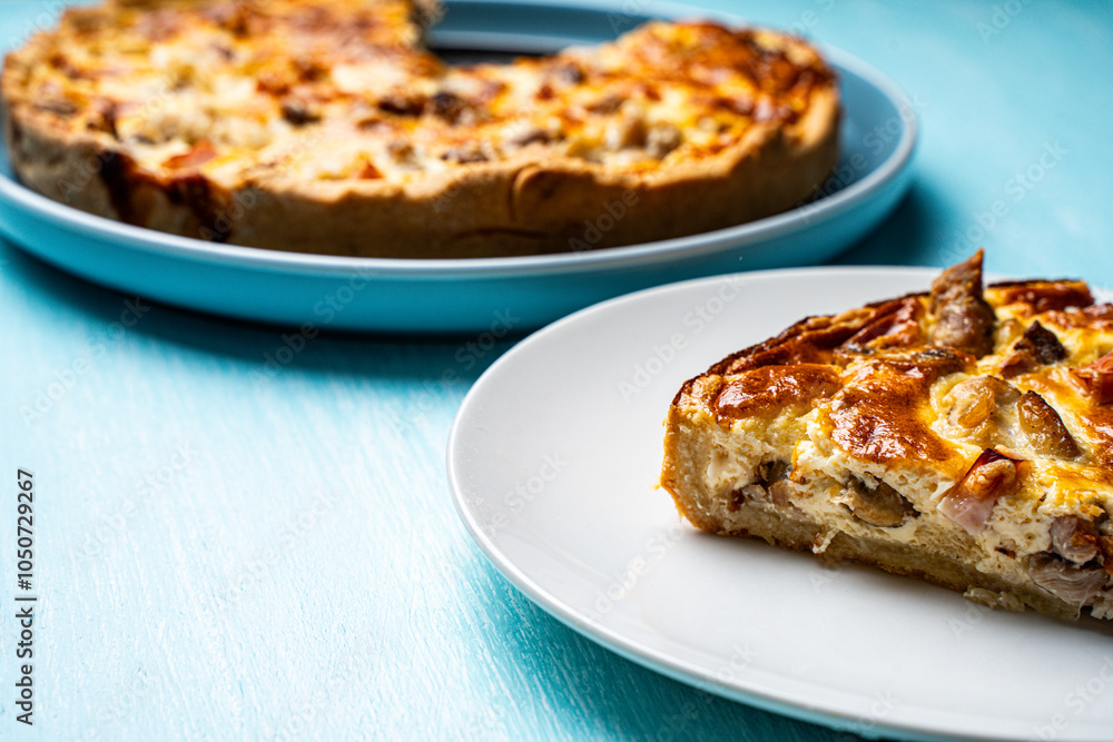 Quiche Laurent according to a traditional French recipe. Pie with chicken and mushrooms on a blue plate with a light blue napkin on a blue background. Quiche Laurent according to a traditional French recipe. Pie with chicken and mushrooms on a blue plate with a light blue napkin on a blue background.