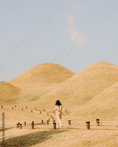 Back view of a young woman walking on a sandy landscape photo