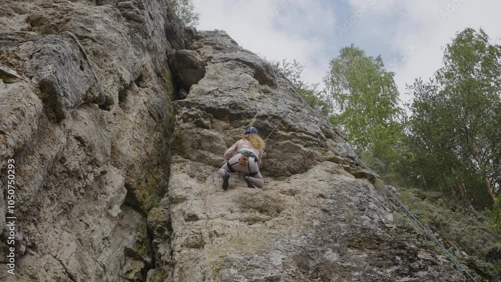 Woman bravely climbing a rugged cliff face, showcasing rock climbing techniques amidst a scenic outdoor backdrop of trees and sky Woman bravely climbing a rugged cliff face, showcasing rock climbing techniques amidst a scenic outdoor backdrop of trees and sky