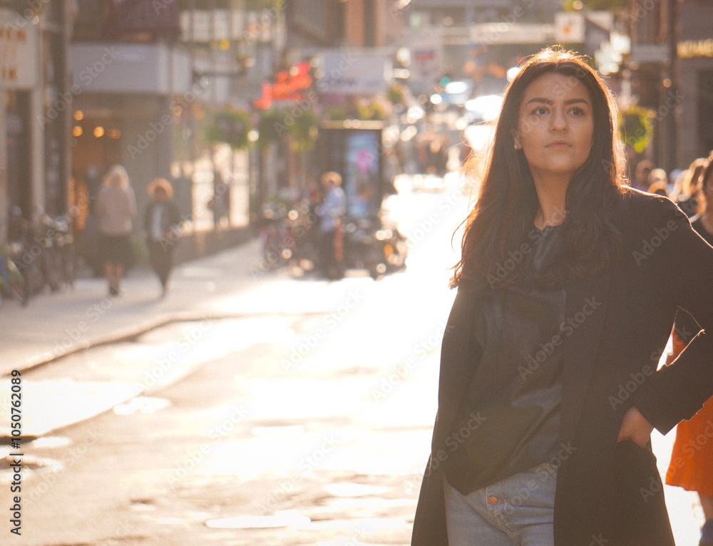 Fototapeta premium A young woman standing in the city with a street in the background