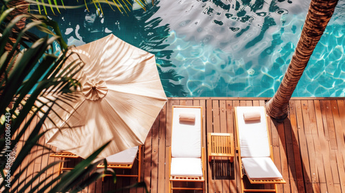 Two poolside loungers under an umbrella on a wooden deck by a turquoise pool, surrounded by tropical greenery. photo