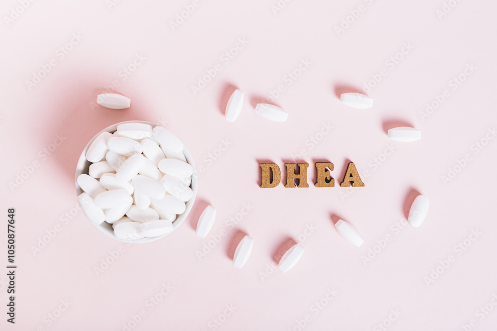 Hormonal supplement DHEA in tablets in a bowl on a pink background