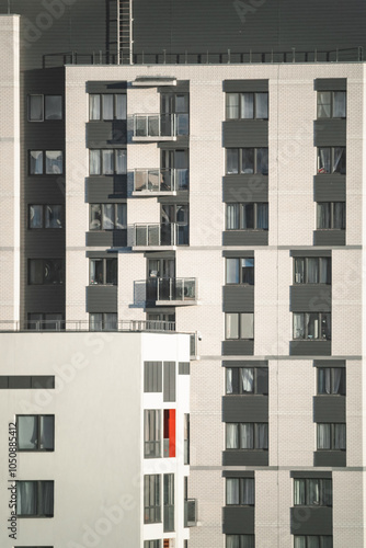 Modern apartment building with multiple balconies located in an urban area reflecting afternoon sunlight and showcasing contemporary architecture