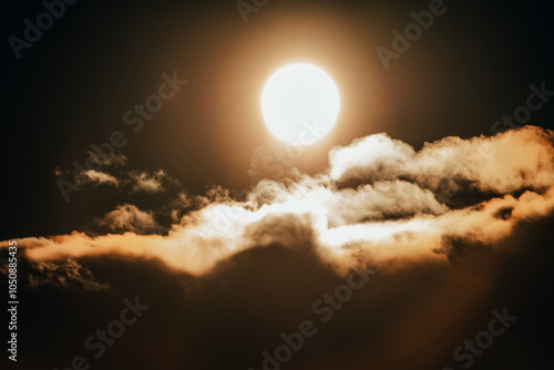 Bright sun illuminating fluffy clouds at dusk over a serene landscape, creating a warm golden glow in the sky