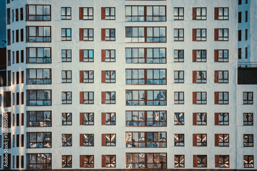 Modern apartment building with multiple balconies located in an urban area reflecting afternoon sunlight and showcasing contemporary architecture