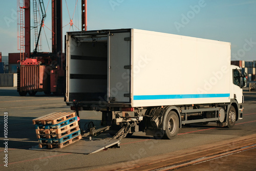 Moving Delivery Cargo Truck With Refrigerated Trailer With Wooden Pallets On Hydraulic Ramp photo