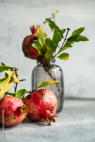 Vibrant whole pomegranates with green leaves in glass jar photo