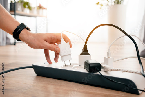 Person is plugging in a device to a power strip photo