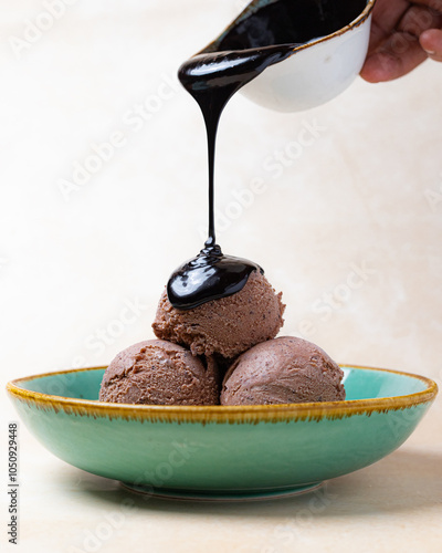 Man pouring hot chocolate sauce on ice cream photo