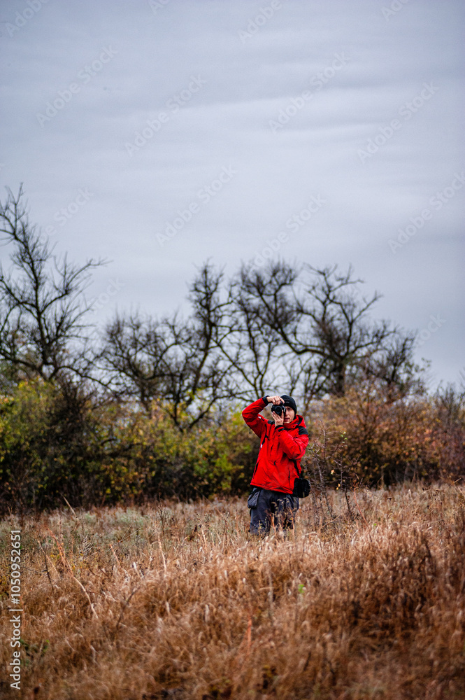 Man in the forest , landscape photographer in work , camera man hiking in the forest , autumn forest ,sunrise . Photographu in forest . Man with hat , brutal boy walking in forest Man in the forest , landscape photographer in work , camera man hiking in the forest , autumn forest ,sunrise . Photographu in forest . Man with hat , brutal boy walking in forest