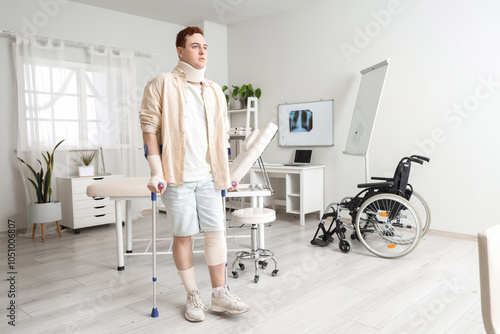 Injured young man after accident with crutches in clinic photo