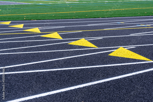 Close up of yellow exchange zone markings on a new black running track with white lane lines.	 photo