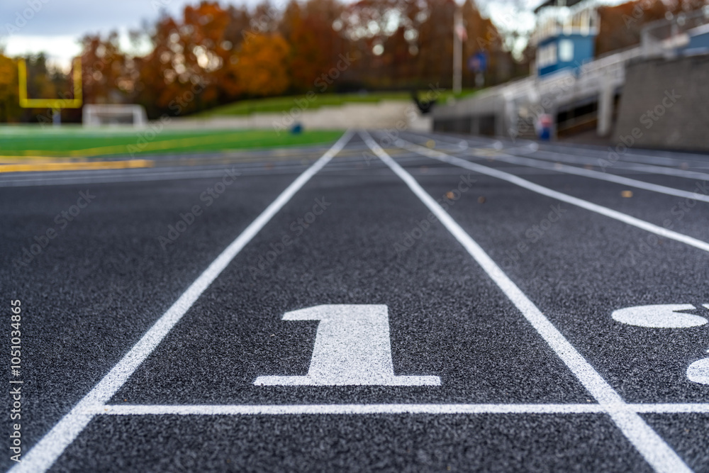 Close up lane number 1 on a new black running track with white lane lines and other markings. Close up lane number 1 on a new black running track with white lane lines and other markings.