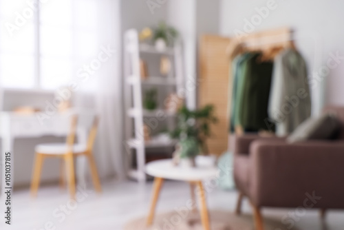 Blurred view of dressing room with clothes rack, armchair and table