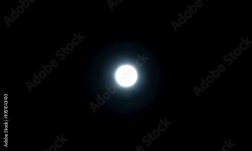 A bright white moon shining in the dark night sky.