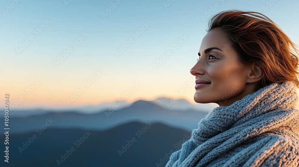 Fototapeta premium Woman in a warm scarf enjoying a peaceful moment in the mountains at sunset.
