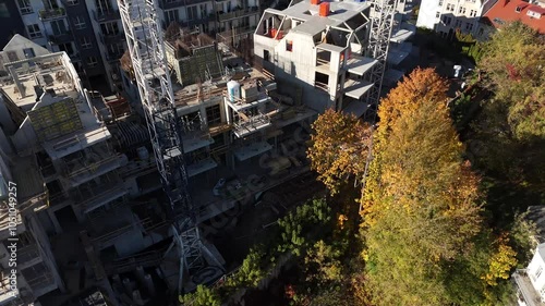 Aerial view of residential construction in Vilnius Old Town, featuring cranes, modern buildings, and autumn foliage.